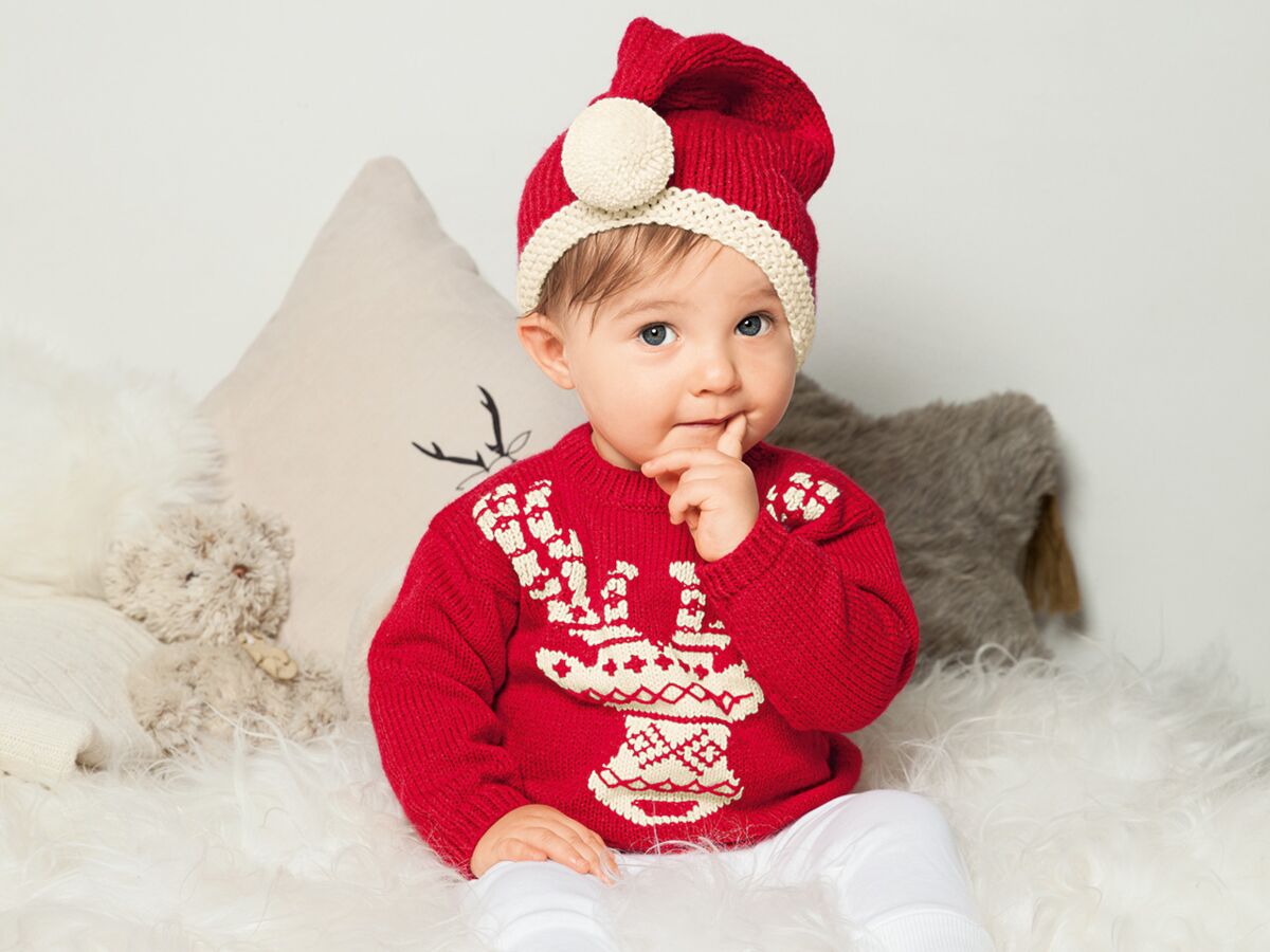 Bébé Dans Un Bonnet De Noël Dans Un Pull Et Des Chaussettes En Laine Sur Un  Traîneau Dans Un Intérieur Du Nouvel An