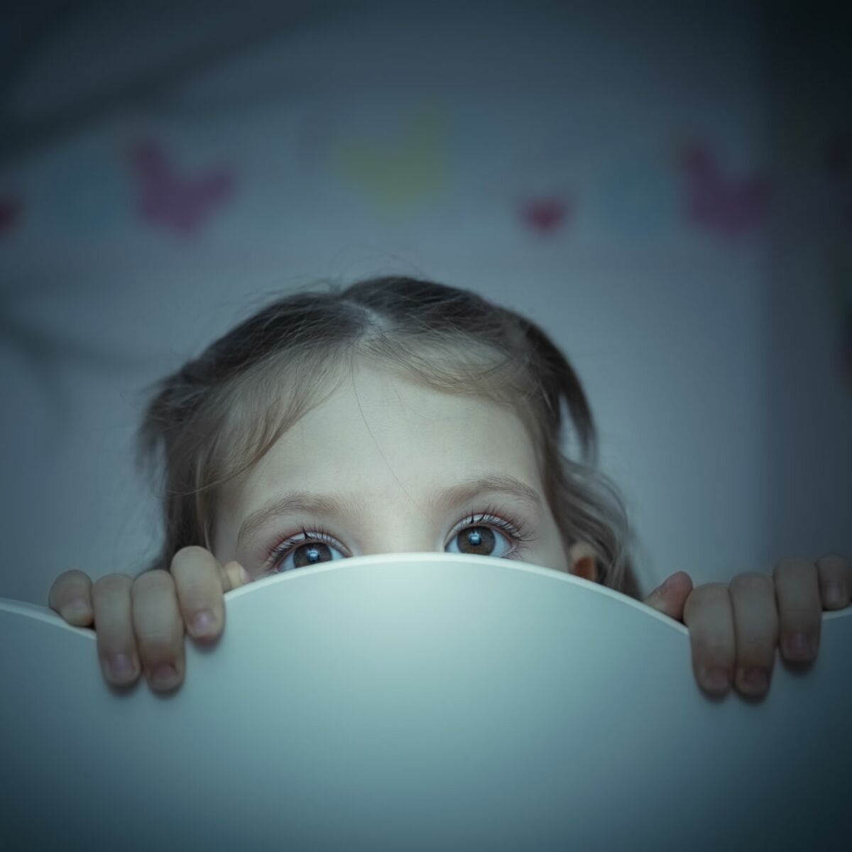 Petite Fille Se Trouve Dans Son Lit Dans Un Bonnet De Nuit Avec Un Livre  Pour Enfants Et Sourit