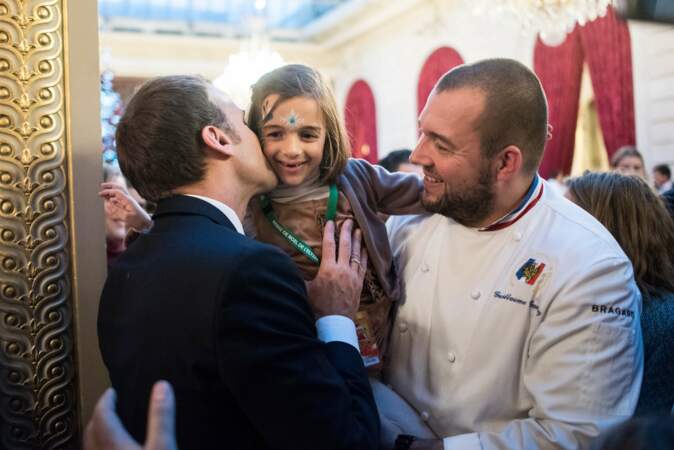 Emmanuel Macron embrasse une enfant portée par le chef Guillaume Gomez