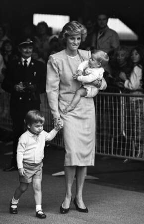 La princesse Diana portant Harry et tenant le prince William par la main, en 1985.