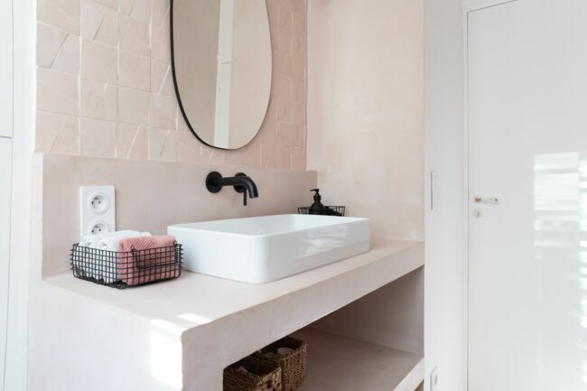Le meuble vasque maçonné et sa crédence ont été recouverts d’un béton ciré rose poudré assorti aux zelliges. (Agence d’architecture Studio Castille.) 