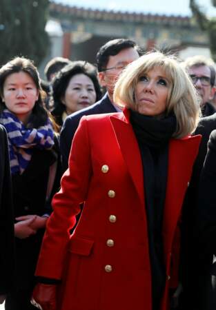 Brigitte Macron en long manteau rouge à boutons dorés et col roulé noir