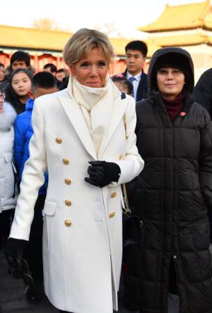 Brigitte Macron en long manteau blanc à boutons dorés et pull à col roulé 