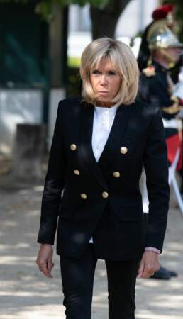 Brigitte Macron en veste blazer noire à boutons dorés et chemise blanche