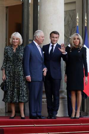 Visite de Charles III : Brigitte Macron en robe bleu marine et sangles aux épaules et Camilla Parker Bowles en longue robe fluide imprimé léopart 