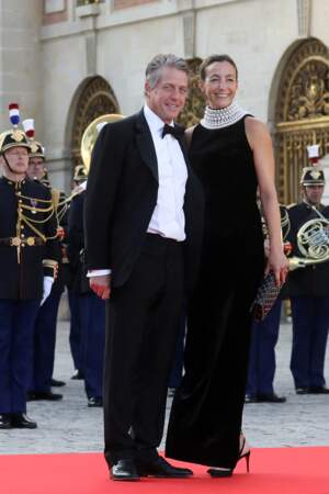 Visite de Charles III : Hugh Grant et femme Anna Elisabet Eberstein en robe longue noire au col perlé élégant 