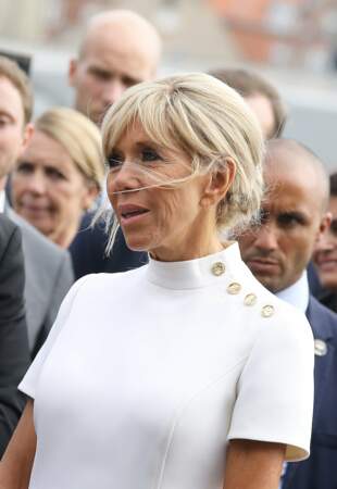 Brigitte Macron en robe blanche à manches courtes à col montant et gros boutons dorés
